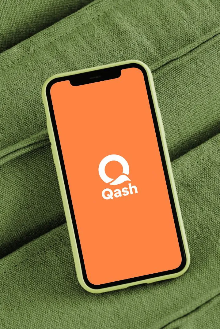 Ponsel dengan layar pembuka Qash di atas kain kanvas hijau
